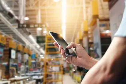 Factory worker using application on mobile smartphone to operrate automation for modern trade. Checking order in large warehouse. Import and export the shipping cargo.