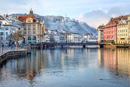 Lucerne city, Switzerland, view of the Old Town covered with white snow in winter, reflecting in the river