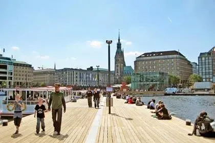Hamburg, Germany - May 22, 2008: Pier of Lake Binnenalster - people relaxing - excursion boats starting from here for trips on the Alster. Historic town hall in the background