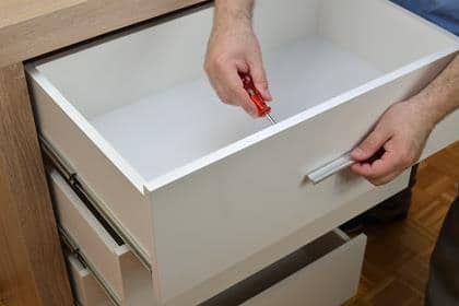 Man's hands fastening a handle of a drawer