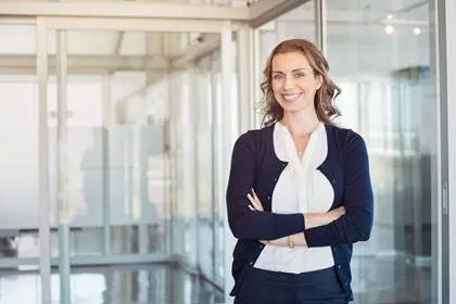 Portrait of mature beautiful business woman in the office looking at camera. Business executive standing in modern office with big smile. Cheerful mid businesswoman with copy space.